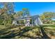 Side exterior view of a charming home featuring a large sunroom and mature trees at 4324 Leafway Cir, Leesburg, FL 34748