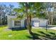 Charming home exterior featuring a well-manicured lawn, palm tree, and an attached two-car garage at 4324 Leafway Cir, Leesburg, FL 34748