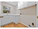 Bright laundry room features white cabinetry, laminate countertops and stainless steel sink and wooden floor at 4324 Leafway Cir, Leesburg, FL 34748