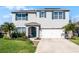 Two story home boasts a manicured lawn, blue shutters, solar panels, and a two car garage at 5363 Timberland Ave, St Cloud, FL 34771