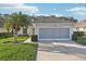 Charming single-story home with a well-manicured lawn, lush landscaping, and a screened two-car garage at 592 Juniper Way, Tavares, FL 32778