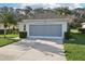 A single story home with a gray garage door, green grass, and landscaping at 592 Juniper Way, Tavares, FL 32778