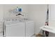 Functional laundry room with a washer, dryer, and wire rack at 620 Vagabond St, The Villages, FL 32163