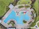 Aerial view of a community pool with a colorful splash pad and plenty of seating at 7193 Dilly Lake Ave, Groveland, FL 34736