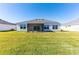 Rear view of home with screened in patio and expansive lawn at 7315 Cornwall Way, The Villages, FL 34762