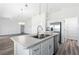 Open kitchen with stainless steel appliances, white cabinets, and an island with double sink at 7315 Cornwall Way, The Villages, FL 34762