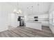 Bright kitchen featuring white cabinets, stainless steel appliances, pendant lighting, and wood-look flooring at 7315 Cornwall Way, The Villages, FL 34762