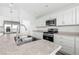 Kitchen with stainless steel appliances, white cabinets, and island featuring a double sink at 7315 Cornwall Way, The Villages, FL 34762