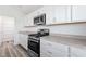 Kitchen features white cabinets, gray countertops, and stainless steel oven and microwave at 7315 Cornwall Way, The Villages, FL 34762
