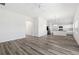 Open-concept living room featuring wood-look floors, white walls, and a kitchen in the background at 7315 Cornwall Way, The Villages, FL 34762