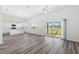 Open-concept living room with a kitchen, wood-look floors and sliding door access to the backyard at 7315 Cornwall Way, The Villages, FL 34762