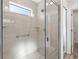 Shower stall featuring glass doors, white tile surround, a window, a shower head and mounted shelves at 7315 Cornwall Way, The Villages, FL 34762