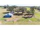 Outdoor image of a barn with a metal roof and gated fence; with lush trees around the barn at 8230 Se 23Rd Dr, Webster, FL 33597