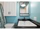 Chic bathroom featuring teal walls, white tiled shower and a vanity with black countertop at 8230 Se 23Rd Dr, Webster, FL 33597