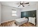 Comfortable bedroom with wood-look flooring, green accent wall, ceiling fan, and white dresser at 8230 Se 23Rd Dr, Webster, FL 33597