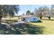 Aerial view of a home with a metal roof, a driveway, and verdant front lawn, creating a welcoming exterior at 8230 Se 23Rd Dr, Webster, FL 33597