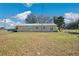 Rear exterior view of home with sliding glass doors, lush lawn and tall communication tower at 8230 Se 23Rd Dr, Webster, FL 33597