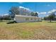 Rear exterior view of home with sliding glass doors, lush lawn and mature trees at 8230 Se 23Rd Dr, Webster, FL 33597