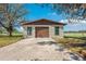 Exterior view of a garage with brown roll-up door and fresh concrete pad on a sunny day at 8230 Se 23Rd Dr, Webster, FL 33597