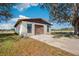 Exterior view of a garage with brown roll-up door, windows, and concrete pad on a sunny day at 8230 Se 23Rd Dr, Webster, FL 33597