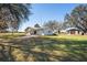 Exterior view of house with lush lawn, mature trees, barn and large parking area at 8230 Se 23Rd Dr, Webster, FL 33597