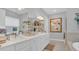 Bright bathroom featuring dual sinks, white cabinets, quartz counters, and decor at 8677 Bridgeport Bay Cir, Mount Dora, FL 32757