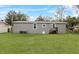 A shot of the backyard with a gray home, green grass and blue skies at 909 Lake Thomas Rd, Lake Wales, FL 33898