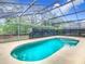 Screened-in pool with clear blue water, surrounded by a concrete deck and lush landscaping at 1007 Balmoral Dr, Davenport, FL 33896