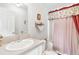 Bathroom with a toilet, sink, and shower with red curtain at 11642 Martell Ct, Leesburg, FL 34788