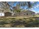 View of the house with a shed in the back yard, and surrounded by lush foliage and large trees at 11642 Martell Ct, Leesburg, FL 34788