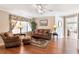 Open living room with wood floors, ceiling fan, comfortable seating and a view into the dining room at 11642 Martell Ct, Leesburg, FL 34788