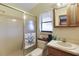 Cozy bathroom with a glass-enclosed shower, vanity and wooden cabinet at 12338 S Putney Ct, Leesburg, FL 34788