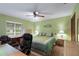 Bedroom with a ceiling fan, light green walls, desk, and dresser at 12338 S Putney Ct, Leesburg, FL 34788