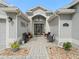 Inviting entrance area with brick-paved walkway, potted plants, and seating area at 1415 Bethune Way, The Villages, FL 32162