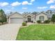 Beautiful home with landscaped front yard, brick driveway, and two-car garage at 1415 Bethune Way, The Villages, FL 32162