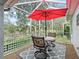 Relaxing outdoor patio featuring a table with seating, pond view and large red umbrella at 1415 Bethune Way, The Villages, FL 32162