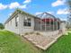 The rear exterior shows a screened-in porch and stone landscaping with lush green grass at 1415 Bethune Way, The Villages, FL 32162