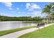 Picturesque pond view with a park bench along a paved path, inviting peaceful moments in nature at 14157 Oasis Cove Blvd # 104, Windermere, FL 34786