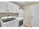 Well-equipped laundry room with white cabinetry and modern washer and dryer units at 14736 Pine Cone Trl, Clermont, FL 34711