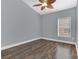 Bright bedroom featuring a ceiling fan, modern window blinds, and stylish wood-look flooring at 16628 Citrus Pkwy, Clermont, FL 34714