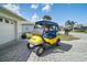 Driveway view of a bright yellow golf cart parked in front of a residential home at 17051 Se 115Th Terrace Rd, Summerfield, FL 34491