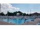 Large outdoor pool with people enjoying the water, surrounded by lounge chairs and tables at 17108 Se 111Th Terrace Rd, Summerfield, FL 34491