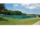 Exterior view of well-maintained tennis courts surrounded by lush green landscaping and clear blue sky at 17108 Se 111Th Terrace Rd, Summerfield, FL 34491