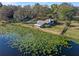 Aerial view of lakefront house surrounded by verdant trees and lily pads at 18944 Bates Ave, Eustis, FL 32736