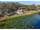 Beautiful aerial view of a lakefront home surrounded by mature trees and water lilies at 18944 Bates Ave, Eustis, FL 32736