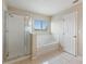 Clean bathroom featuring a glass-enclosed shower and a soaking tub near a window at 201 Andover Dr, Davenport, FL 33897