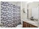 Bathroom featuring a vanity with a granite top, patterned shower curtain, and neutral wall shelves at 215 Elm Ct, Kissimmee, FL 34759