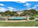 Aerial view of a large community pool with waterfall feature, surrounded by lush landscaping and lounge chairs at 25274 Lost Oak Cir, Leesburg, FL 34748