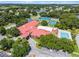 An aerial view of community clubhouse including tennis, shuffleboard, and pool bordered by verdant trees at 27003 Racquet Cir, Leesburg, FL 34748