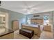 Calm main bedroom featuring neutral walls, bench, ceiling fan, and natural light from two windows at 27003 Racquet Cir, Leesburg, FL 34748